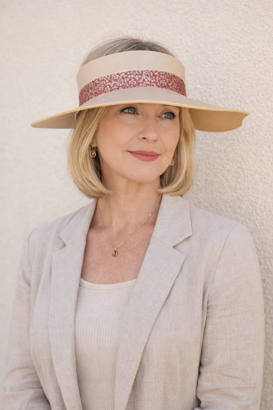 Woman wearing a beige visor and light-colored blazer against a plain background