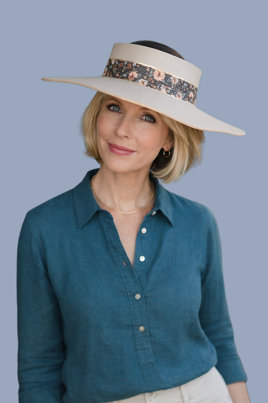 Woman wearing a wide-brimmed hat with a floral band against a blue background