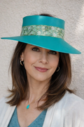 Woman wearing a turquoise visor hat and white cardigan against a neutral background