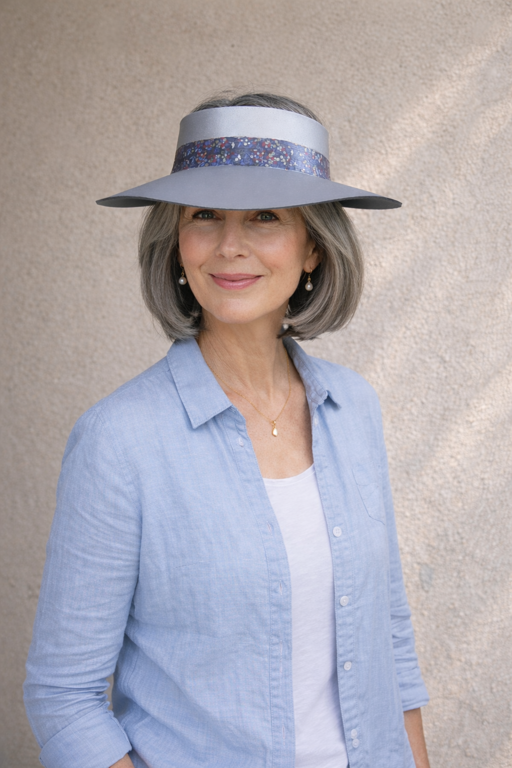 Woman wearing a light blue visor hat against a neutral background