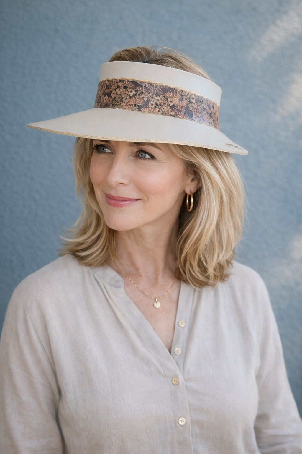 Woman wearing a wide-brimmed hat with a decorative band against a blue background
