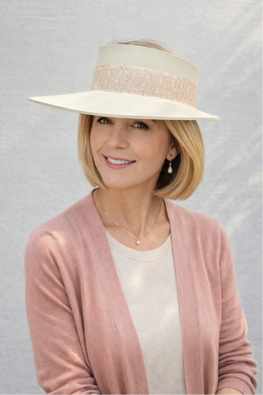 Woman wearing a wide-brimmed hat and pink cardigan against a light gray background