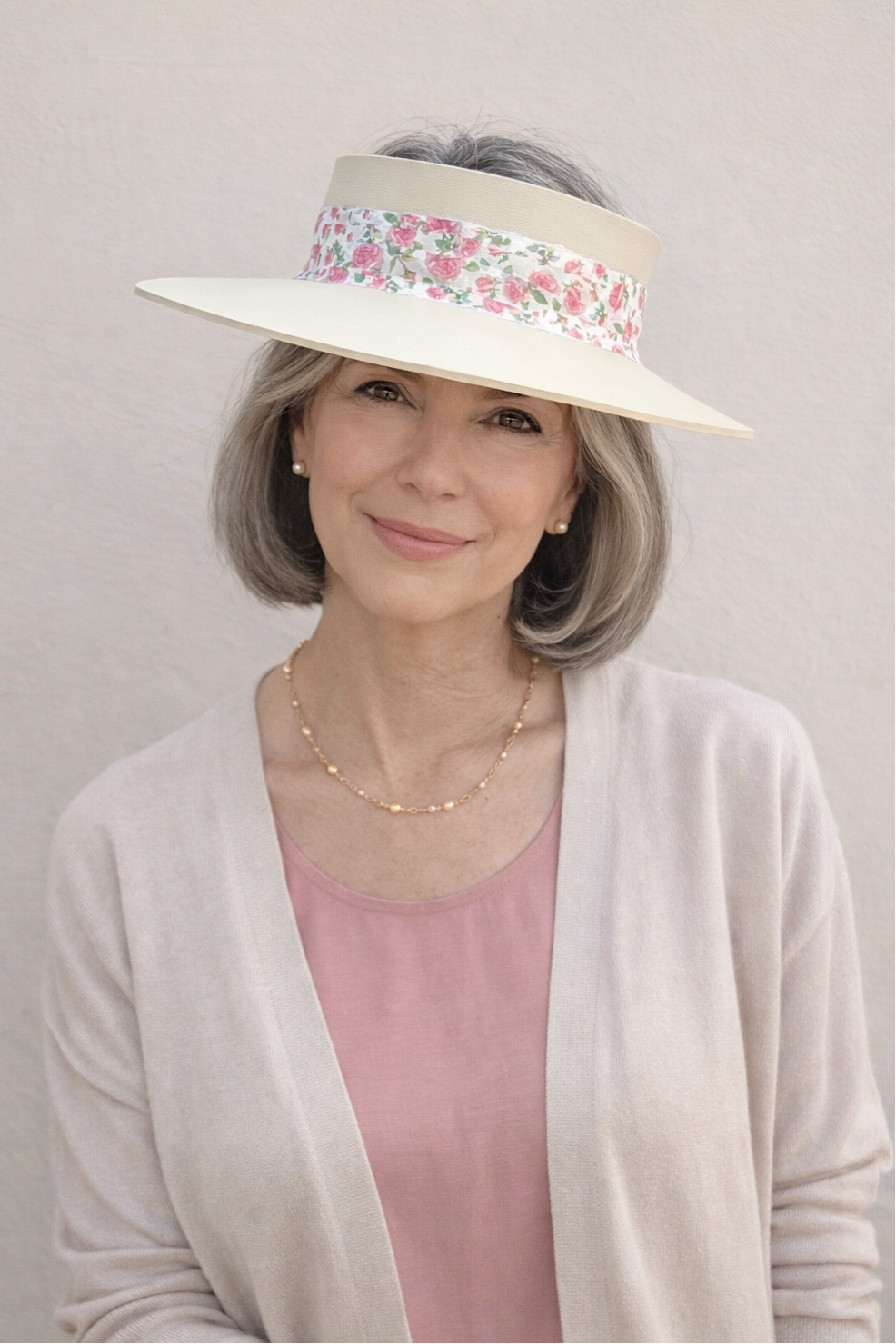 Woman wearing a wide-brimmed hat with floral band against a plain background