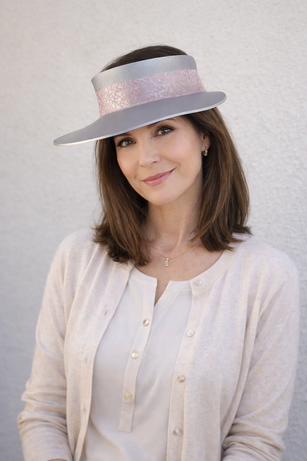 Woman wearing a wide-brimmed hat with a sequined band against a plain background