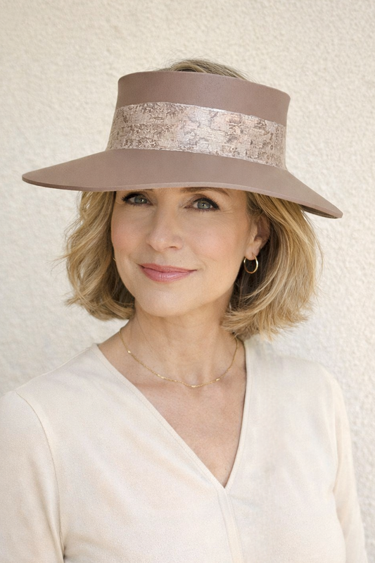 Woman wearing a beige sun visor hat with a patterned band against a neutral background