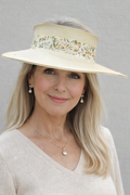 Woman wearing a beige hat with floral embellishments against a gray background