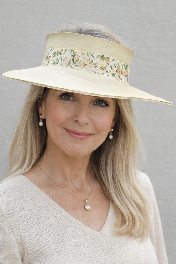 Woman wearing a beige hat with floral embellishments against a gray background