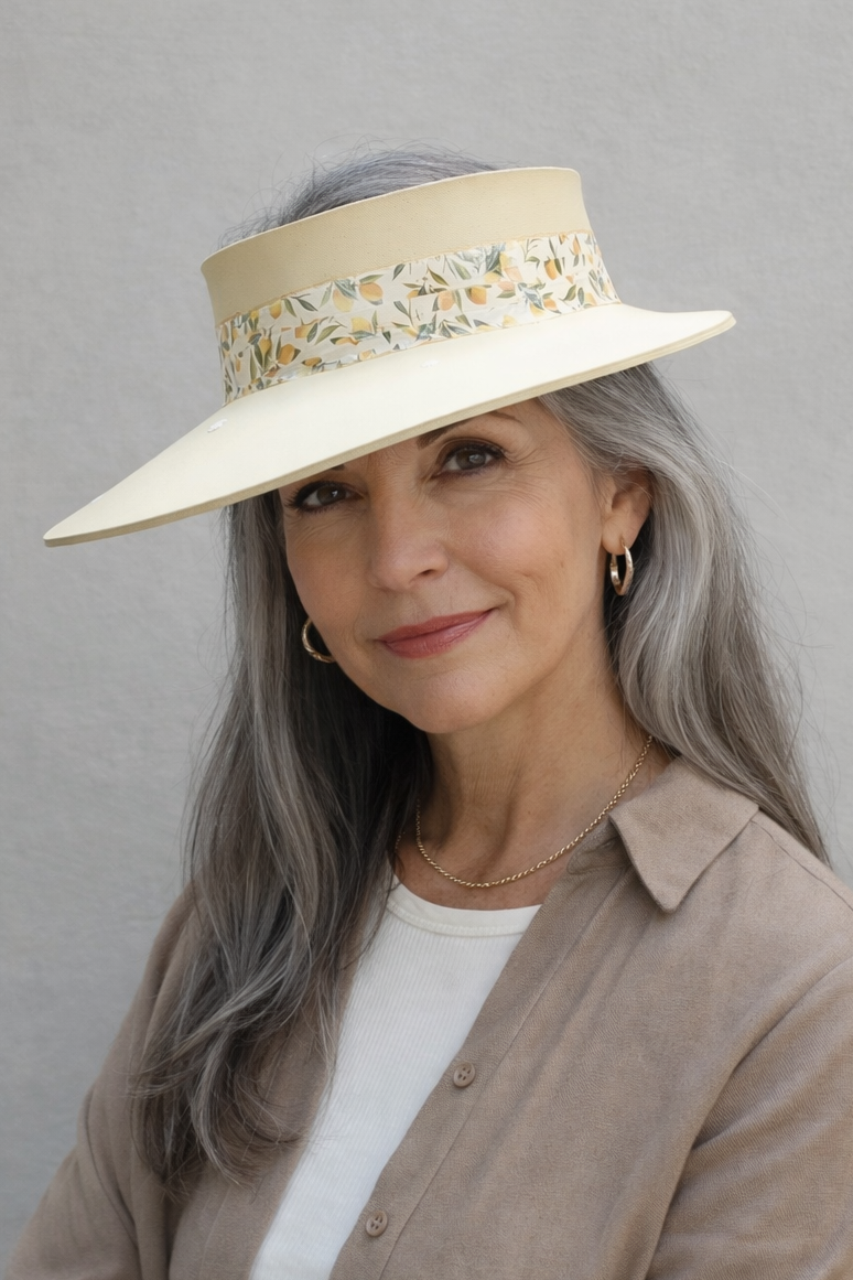 Woman wearing a beige hat with floral details against a gray background