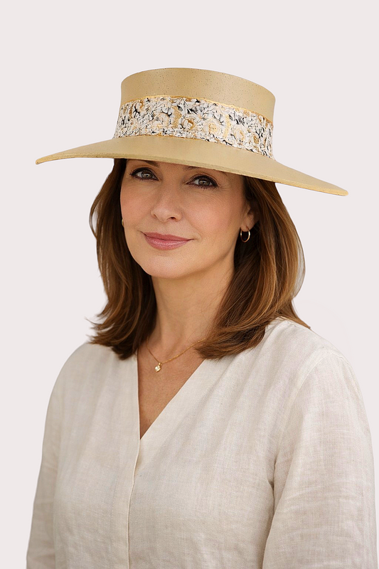 Woman wearing a beige hat with floral embellishments on a white background