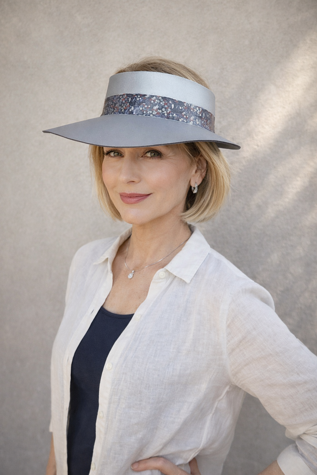 Woman wearing a wide-brimmed hat with a decorative band against a neutral background