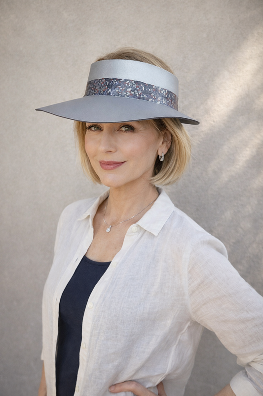 Woman wearing a wide-brimmed hat with a decorative band against a neutral background