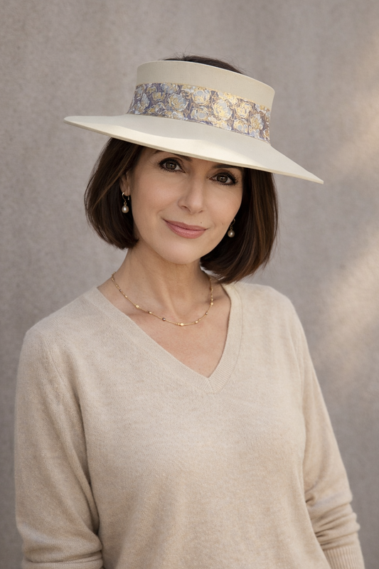 Woman wearing a wide-brimmed hat with floral band against a neutral background
