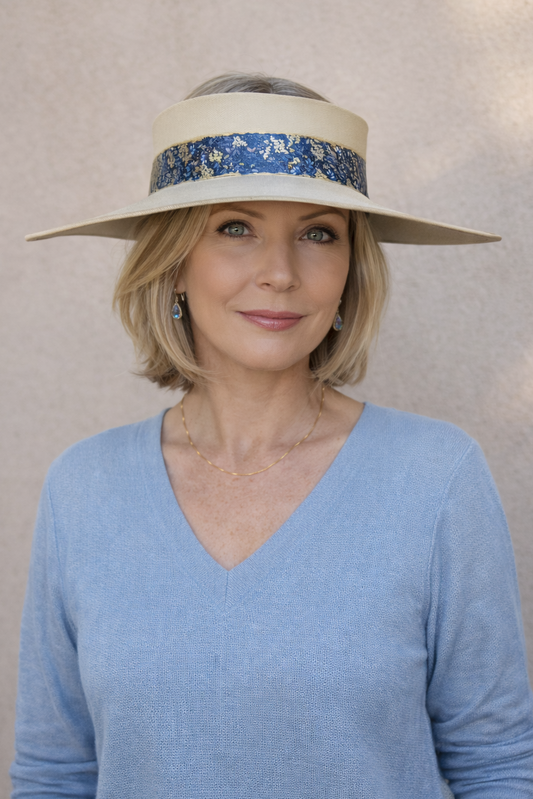 Woman wearing a wide-brimmed hat with a blue band against a neutral background