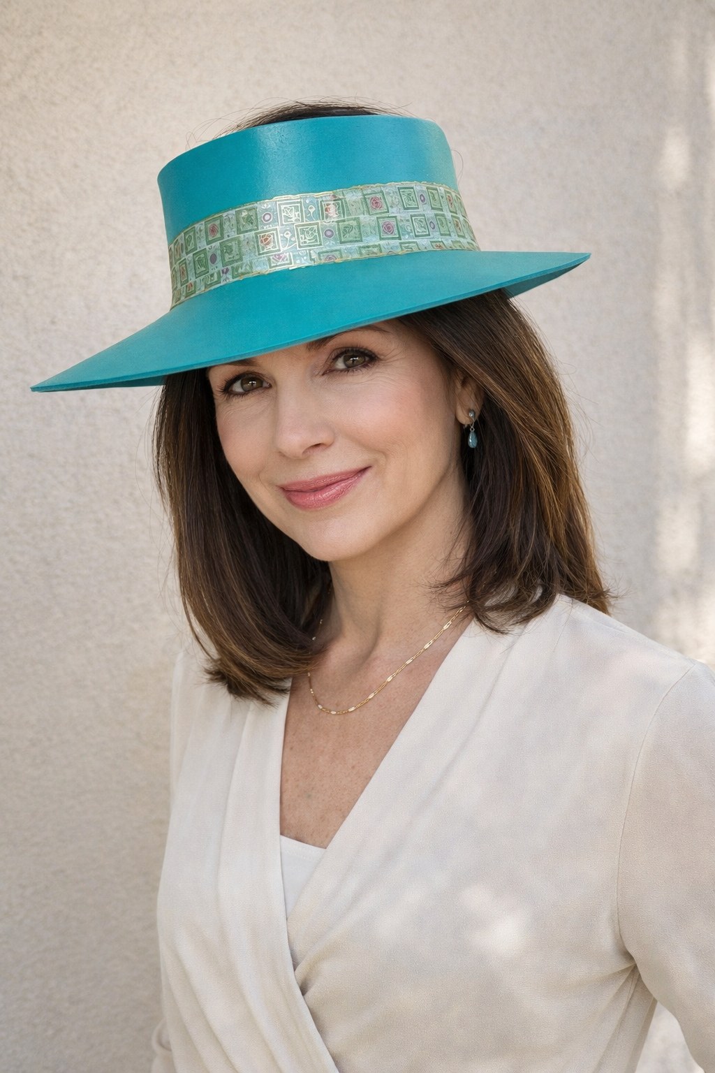 Woman wearing a turquoise hat with a decorative band against a neutral background