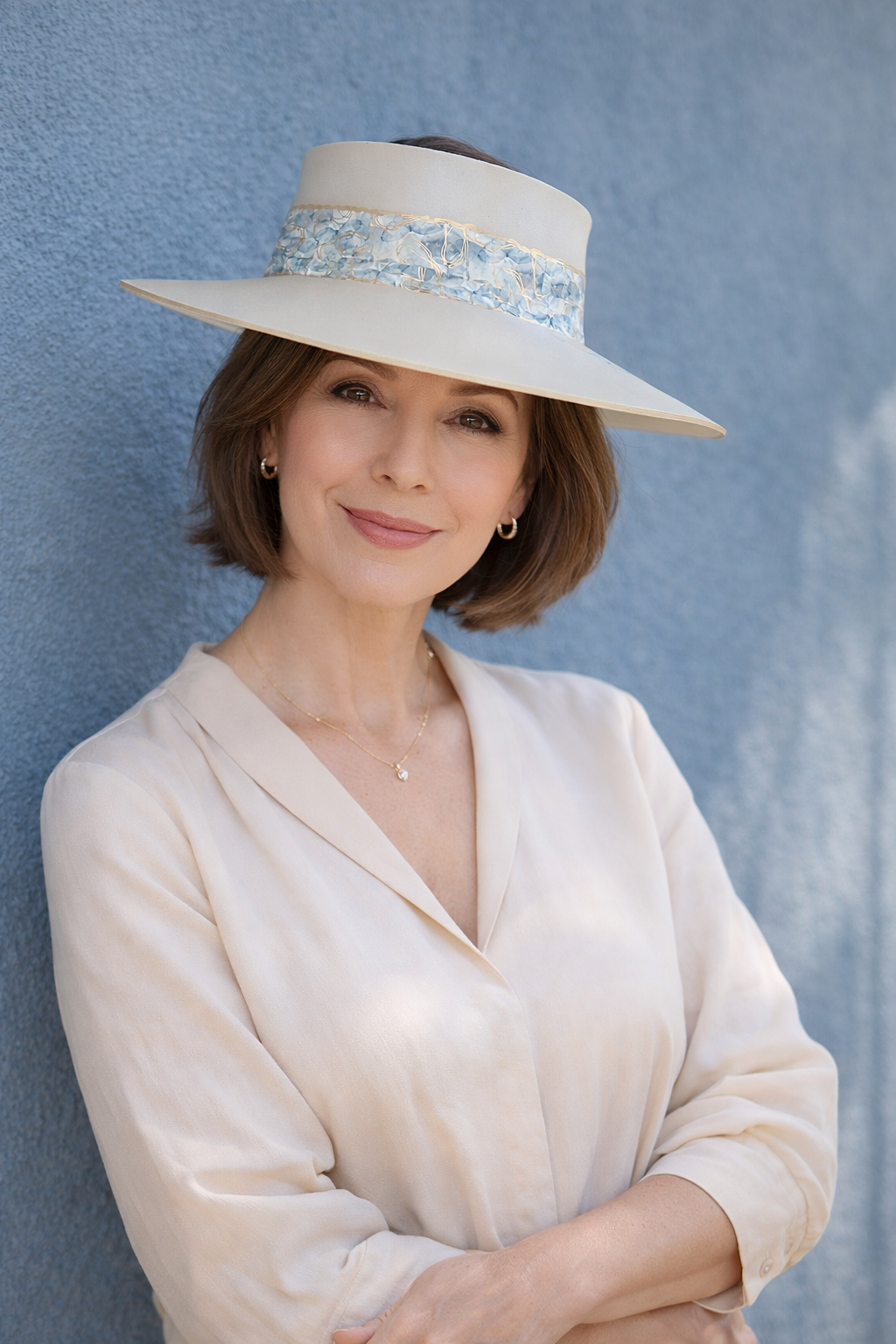 Woman wearing a wide-brimmed hat against a blue wall