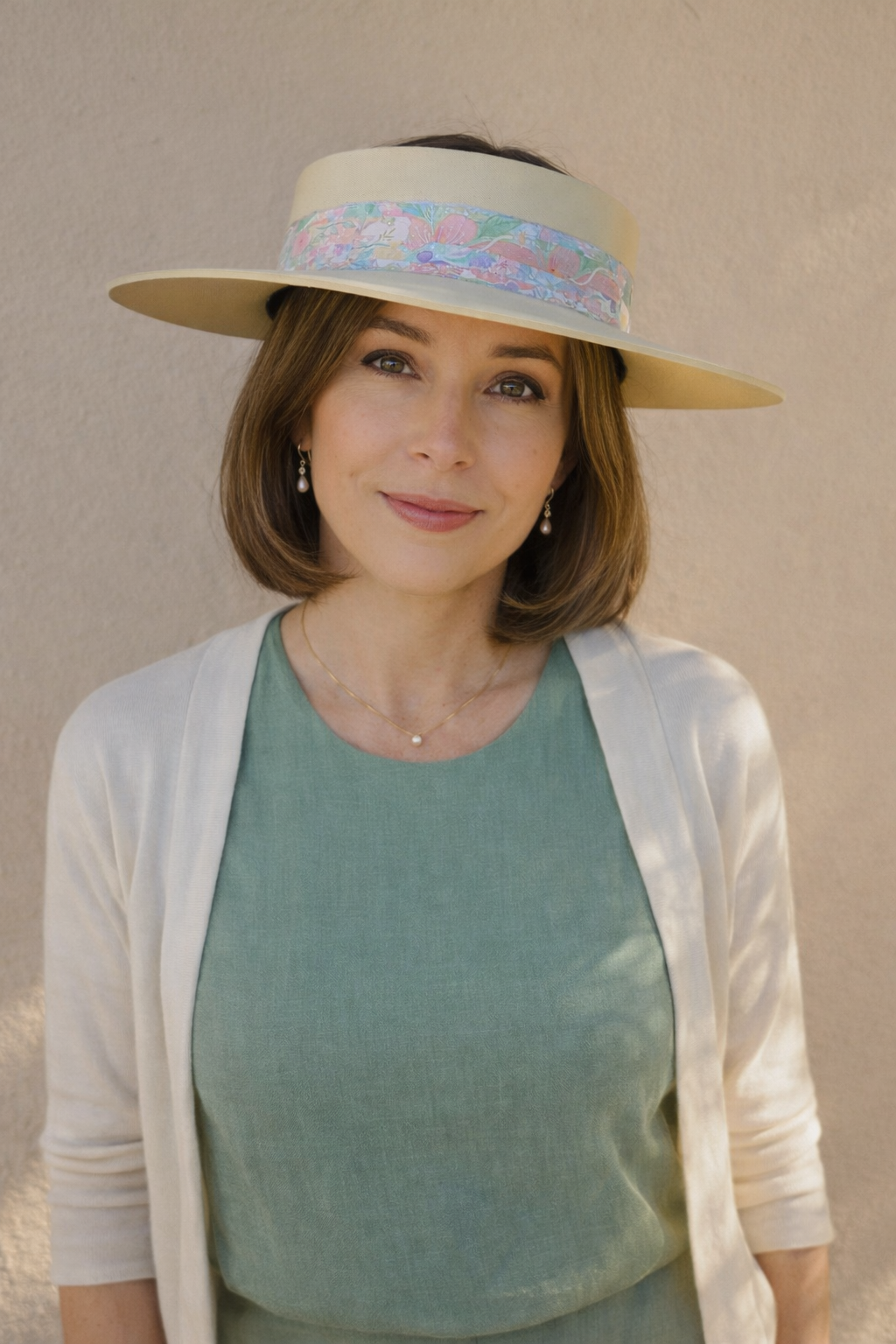 Woman wearing a wide-brimmed hat with a colorful band against a plain background