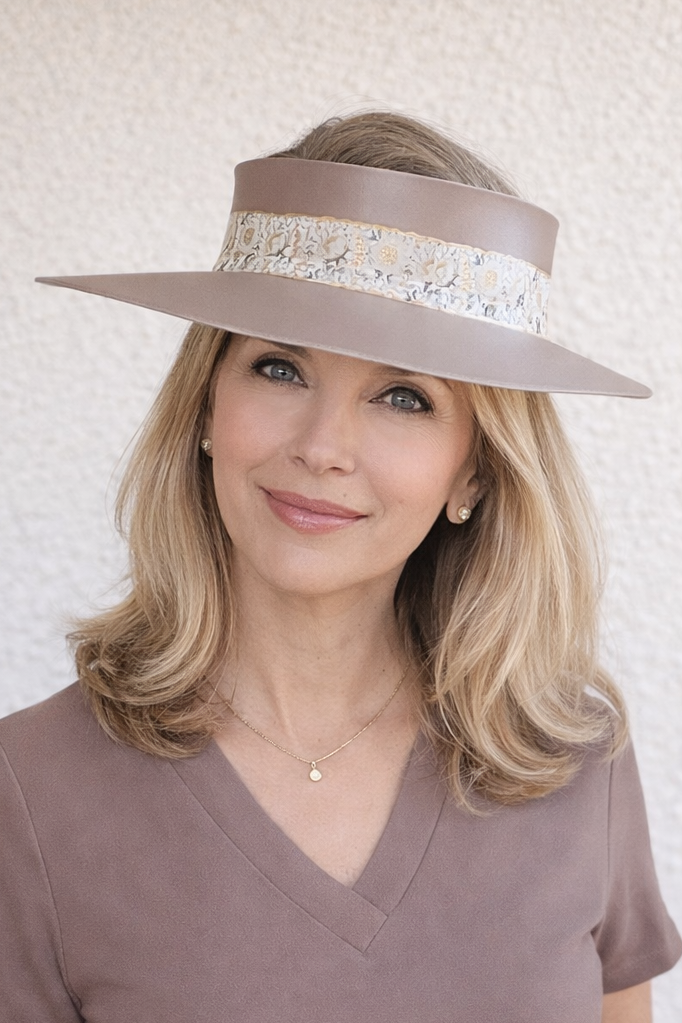 Woman wearing a wide-brimmed hat with a decorative band against a light background