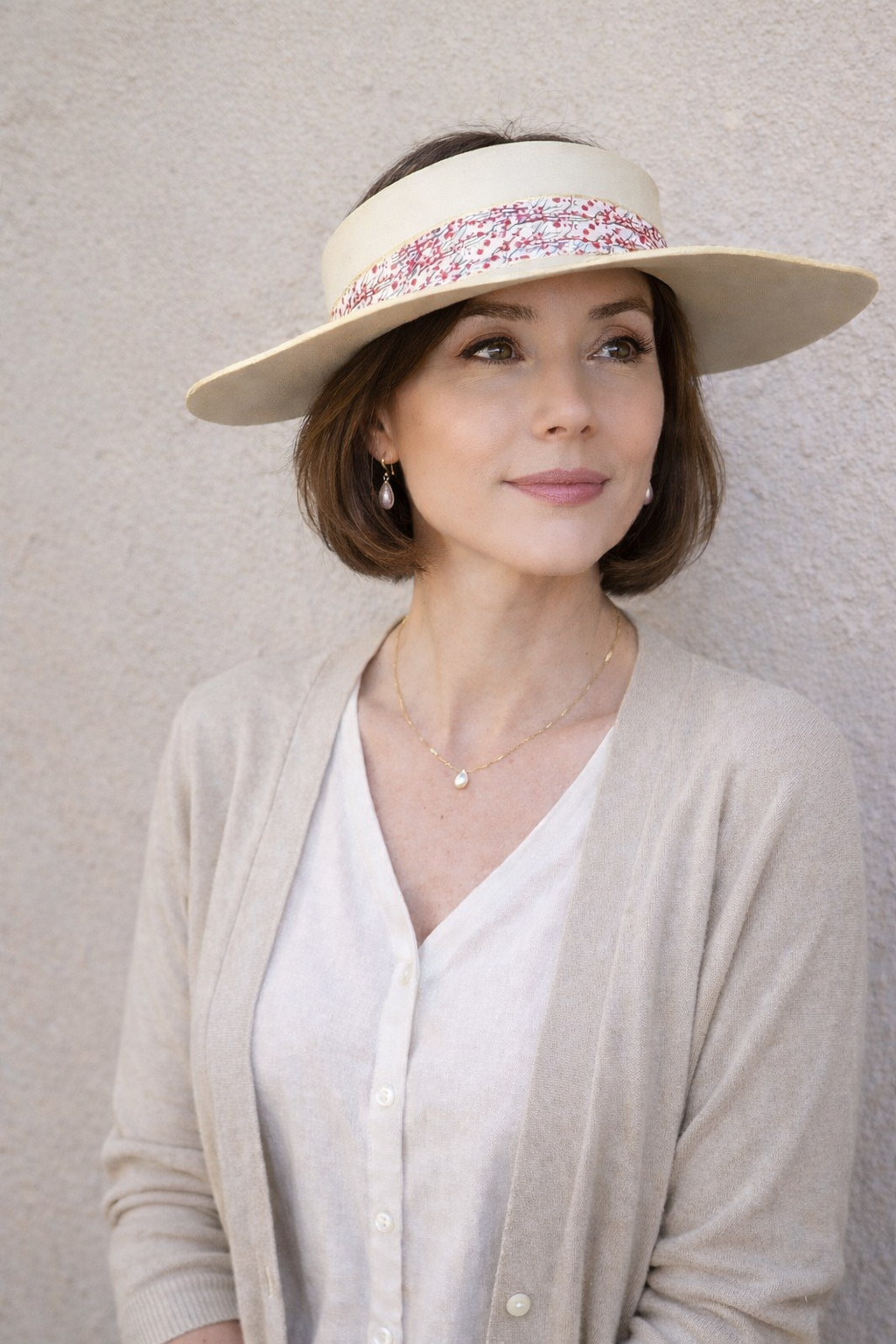 Woman wearing a wide-brimmed hat with a decorative band against a plain background
