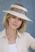Woman wearing a wide-brimmed hat with a sequin band against a textured blue background