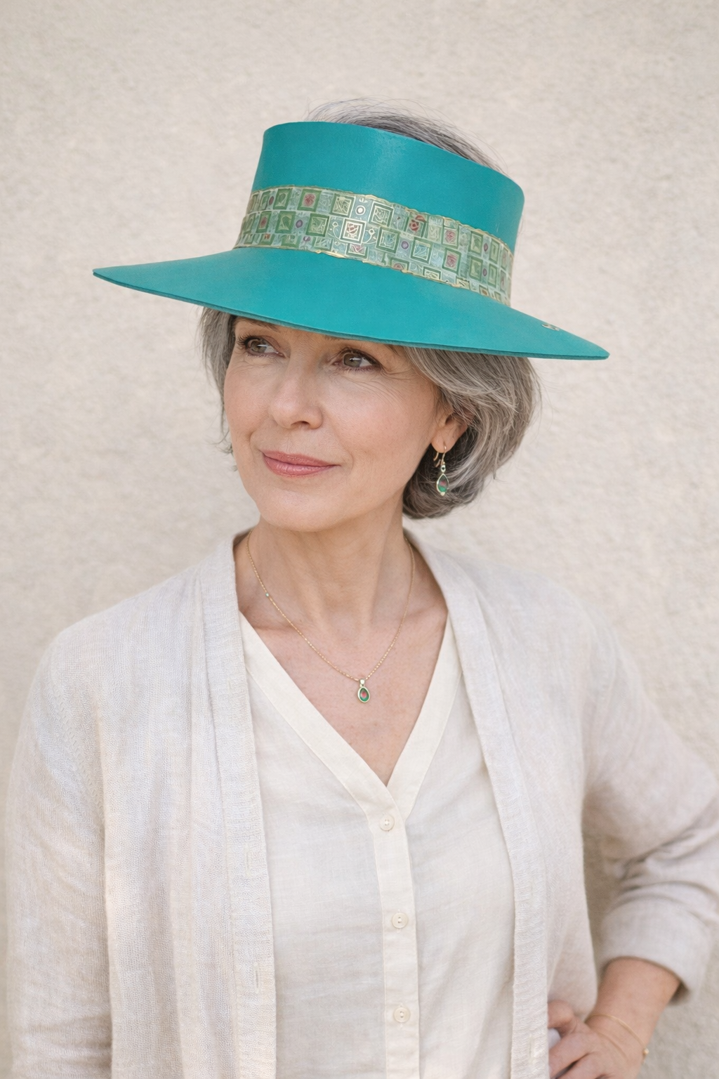Woman wearing a teal sun visor hat against a neutral background
