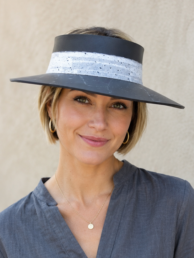 Woman wearing a wide-brimmed hat with a striped band against a neutral background