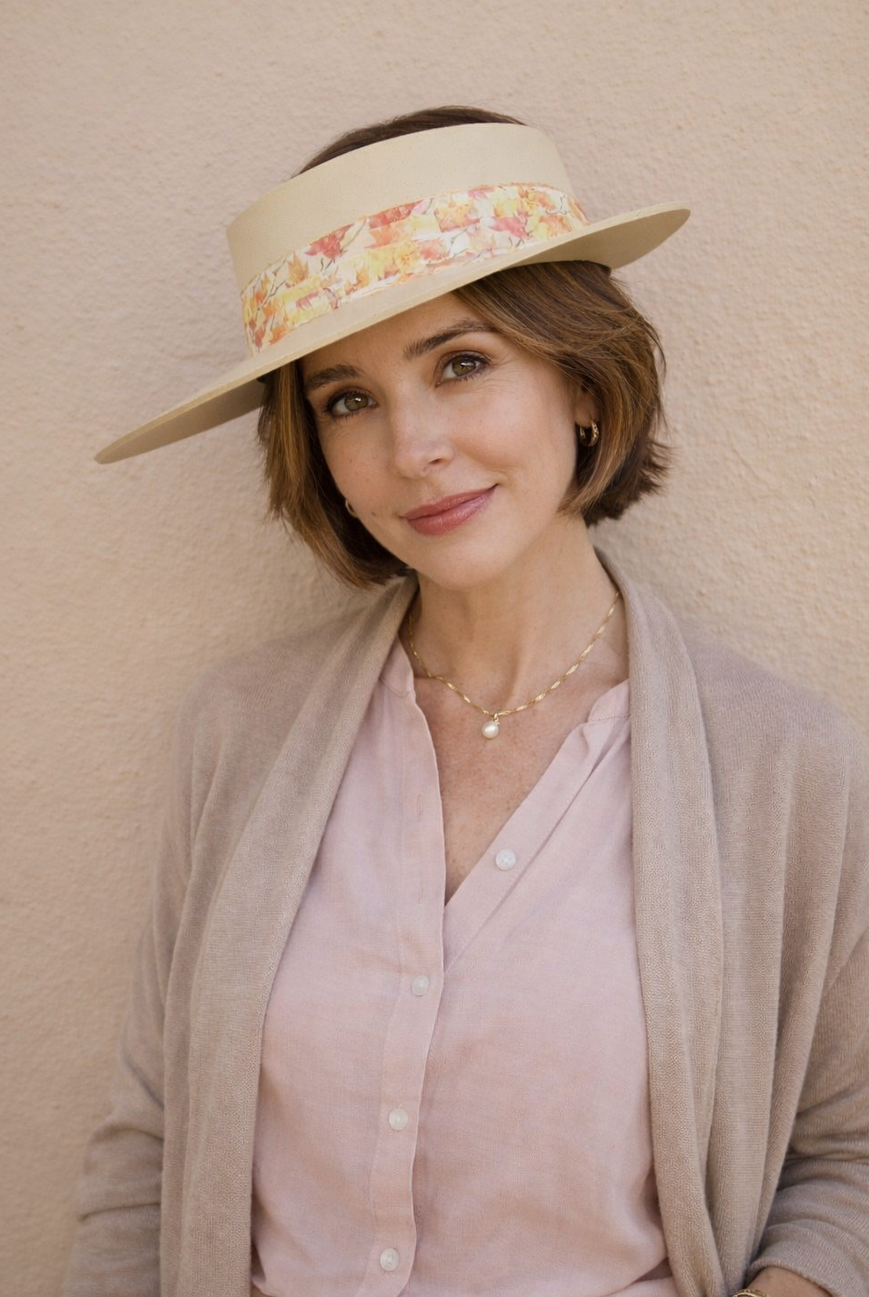 Woman wearing a floral visor hat against a beige wall