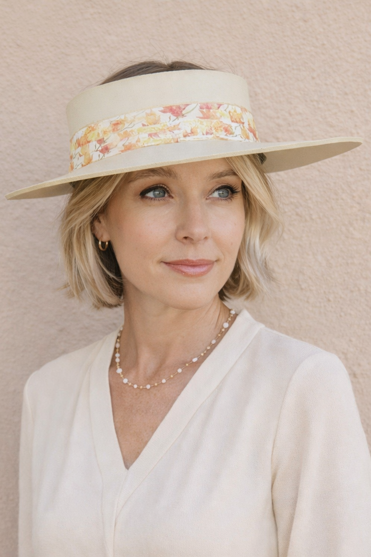Woman wearing a cream-colored visor with floral band and matching outfit against a beige background