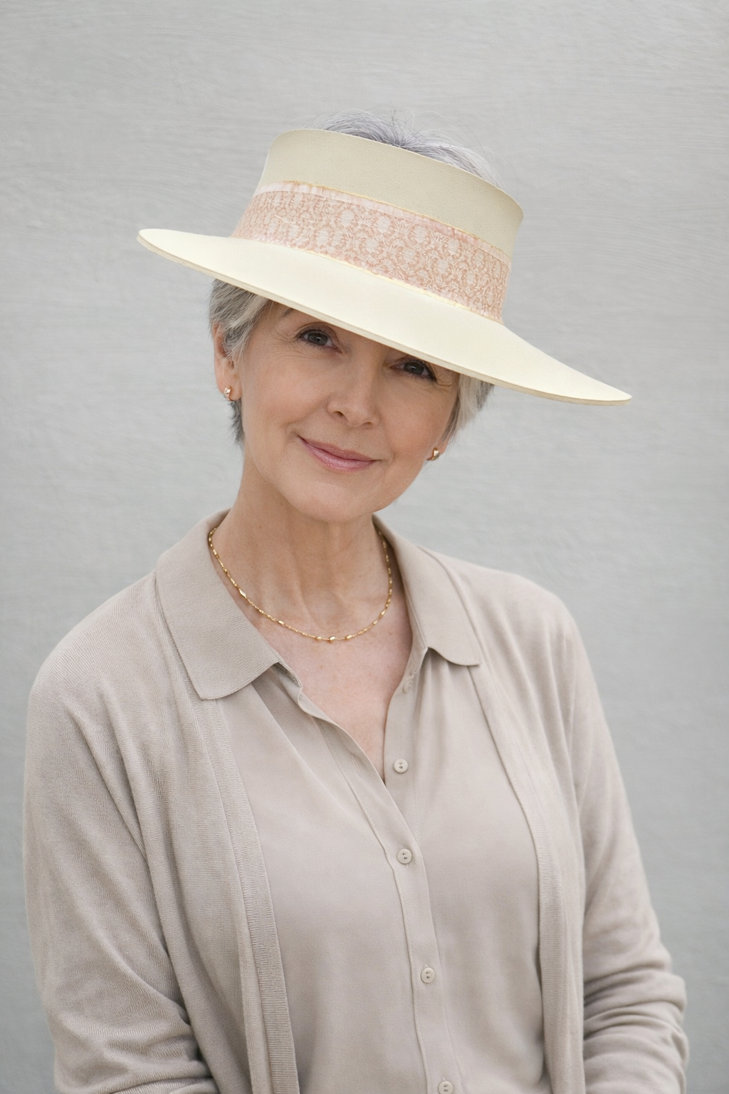 Woman wearing a wide-brimmed beige hat against a gray background