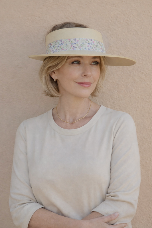 Woman wearing a wide-brimmed hat with a decorative band against a beige background