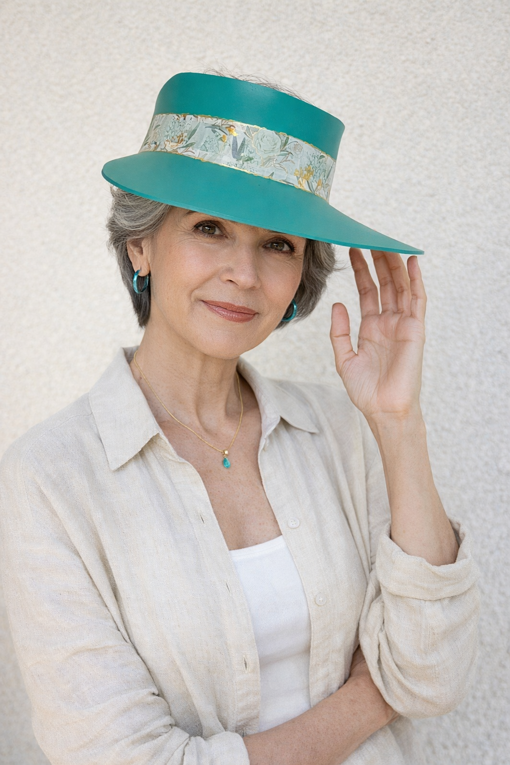 Woman wearing a teal hat with a decorative band against a light background