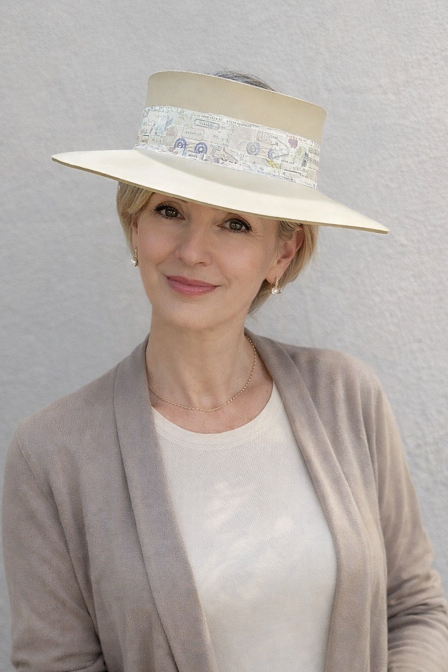 Woman wearing a beige hat with a decorative band against a gray background