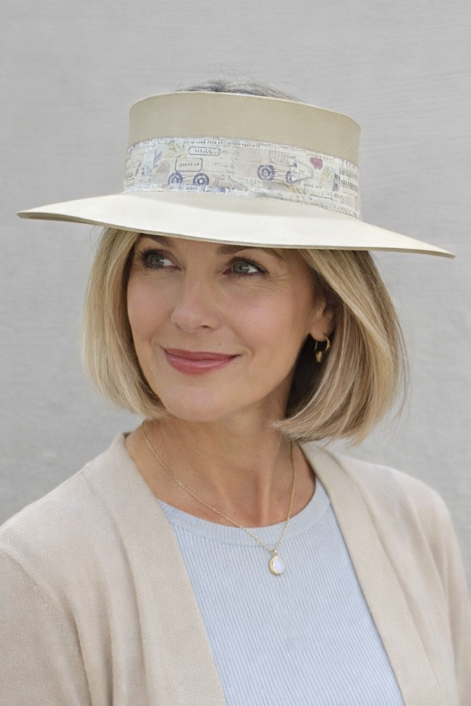 Woman wearing a beige hat with floral band against a gray background