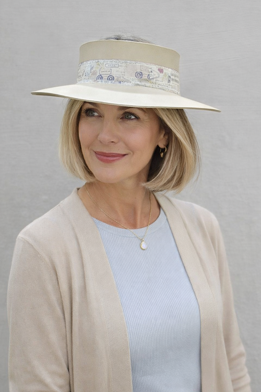 Woman wearing a beige hat with floral band against a gray background