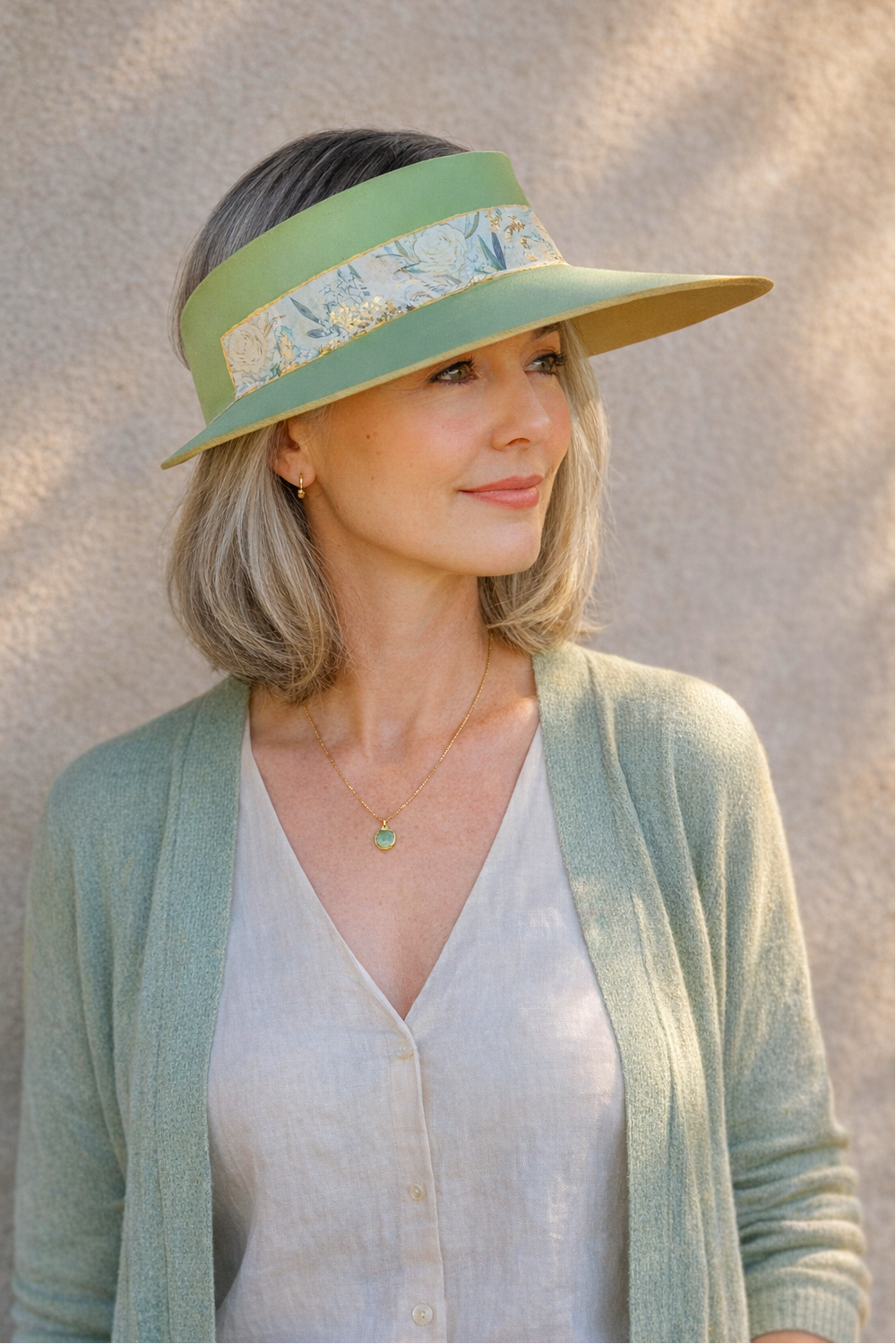 Woman wearing a green visor with floral pattern against a neutral background