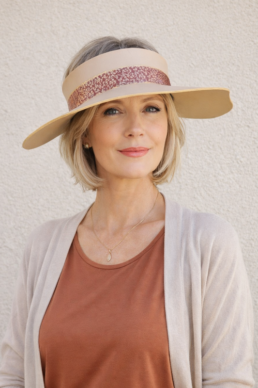 Woman wearing a beige visor and brown top against a light background