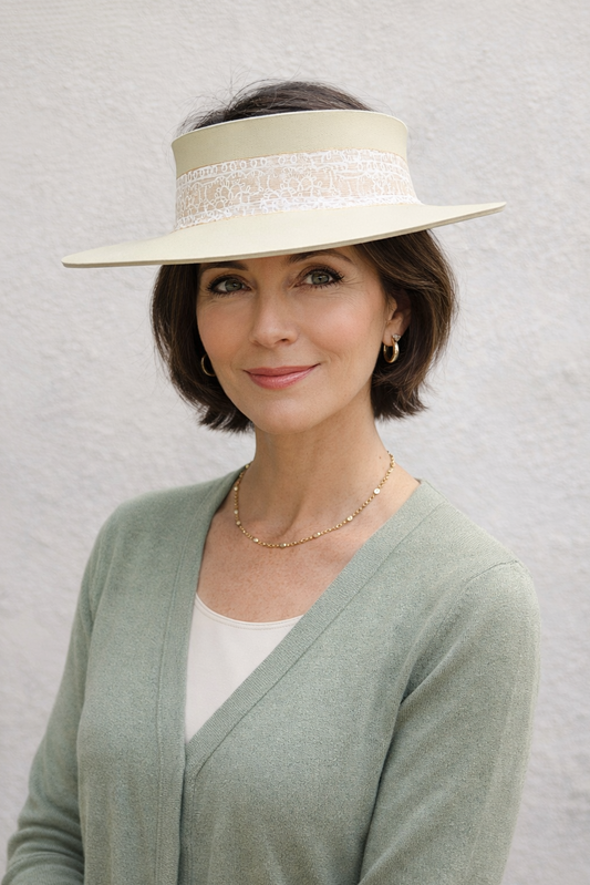 Woman wearing a wide-brimmed hat with lace details against a plain background