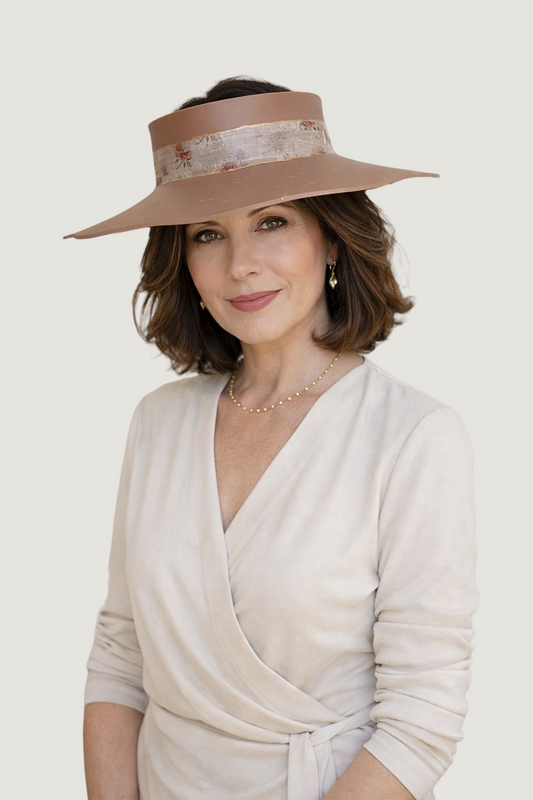 Woman wearing a beige hat and white top on a plain background