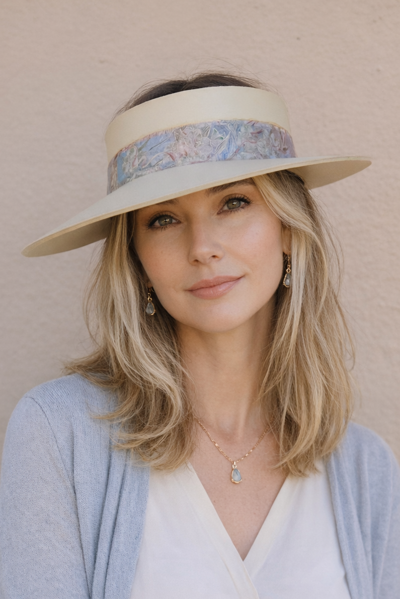Woman wearing a wide-brimmed hat with floral band against a beige background
