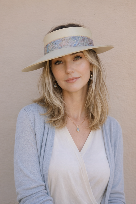 Woman wearing a wide-brimmed hat with floral band against a beige background
