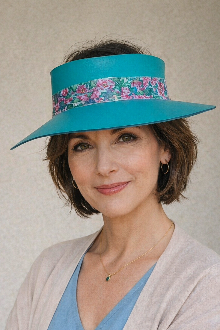 Woman wearing a turquoise hat with floral band against a plain background