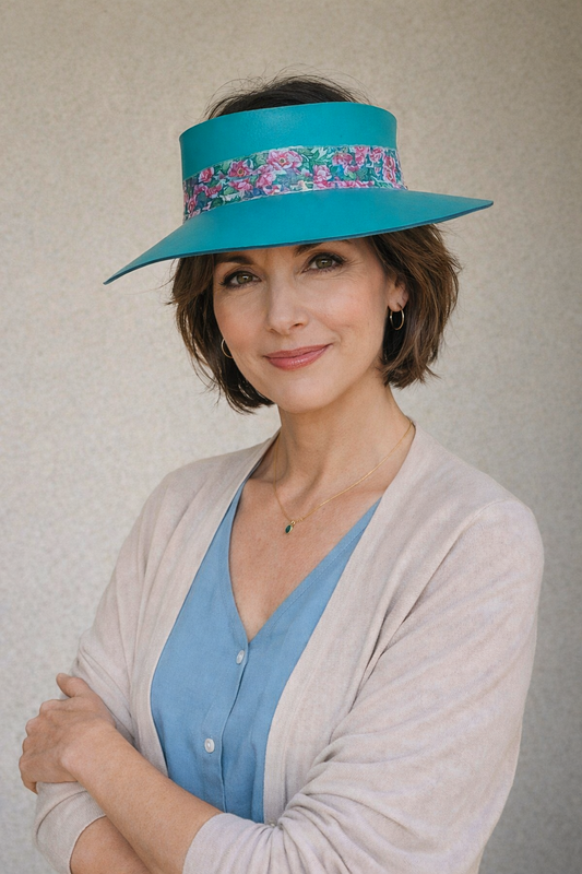 Woman wearing a turquoise hat with floral band against a plain background