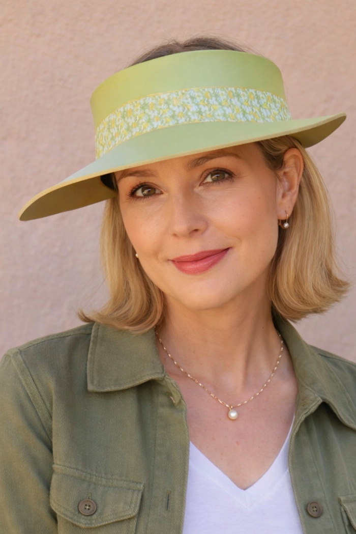 Woman wearing a green visor hat and green jacket against a beige background