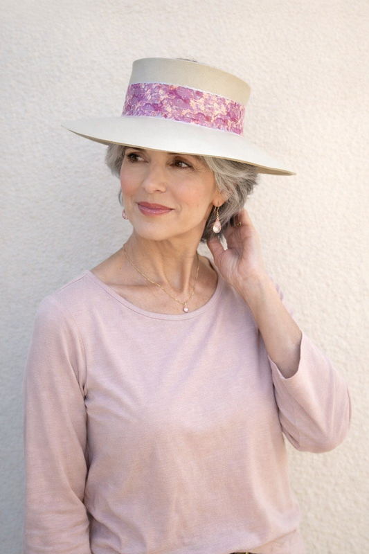Woman wearing a white hat with a colorful band against a plain background