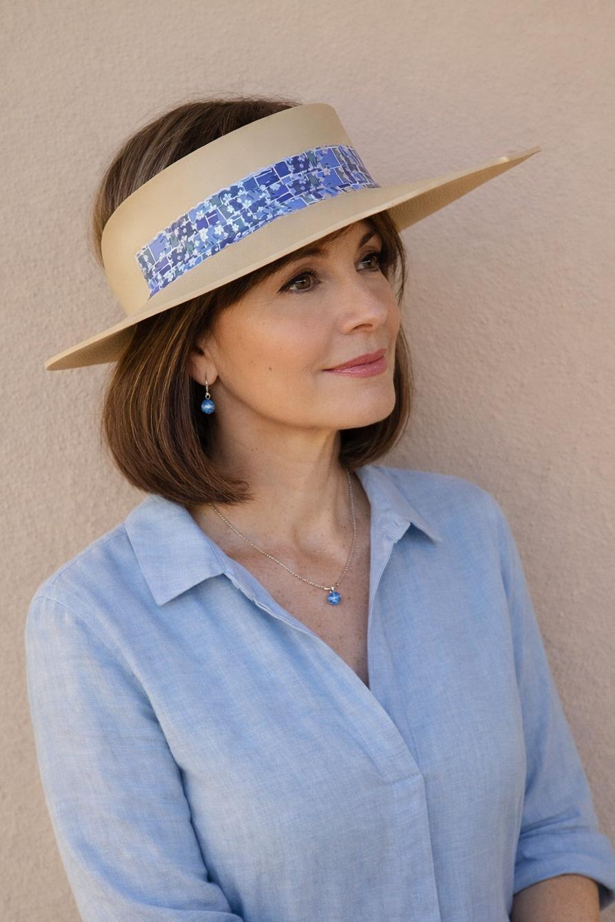 Woman wearing a beige hat with a blue band against a beige wall