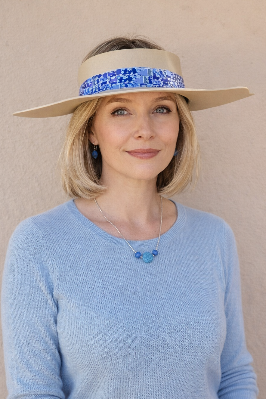 Woman wearing a wide-brimmed hat with a blue band against a beige background