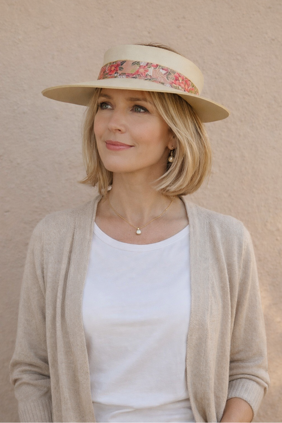 Woman wearing a beige hat with floral band against a beige background