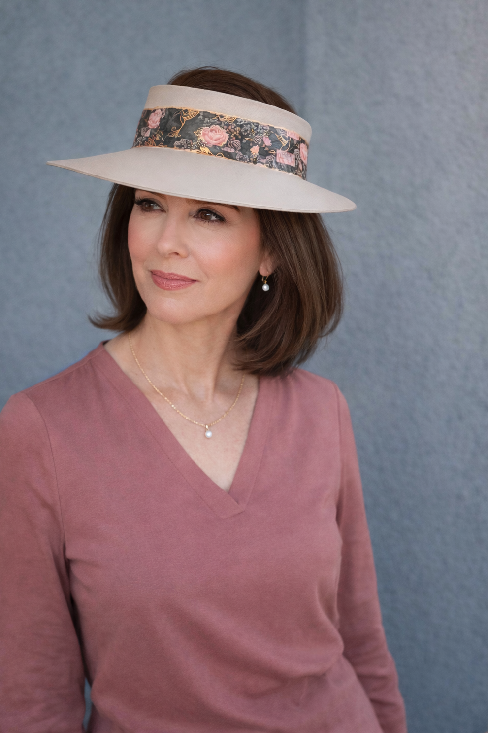 Woman wearing a wide-brimmed hat with floral band against a blue background