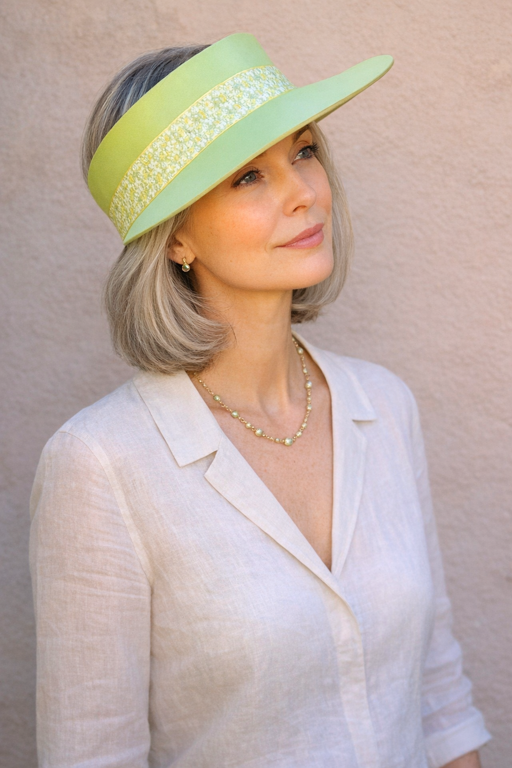 Woman wearing a light green hat with a wide brim against a beige background