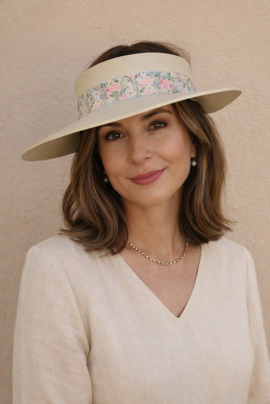 Woman wearing a wide-brimmed hat with floral band against a beige background