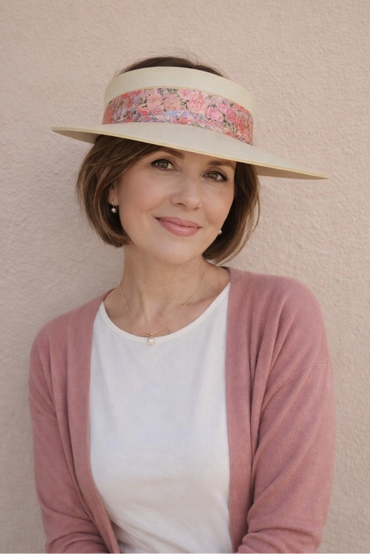 Woman wearing a wide-brimmed hat with a floral band against a beige background